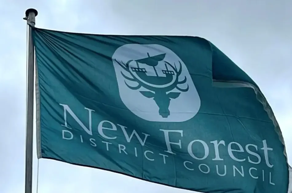 Green flag flying with the New Forest District Council logo featuring a stag's head and a sailing ship.